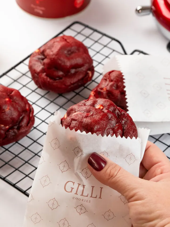 Mão colocando um cookie red velvet no saquinho de papel da Gilli